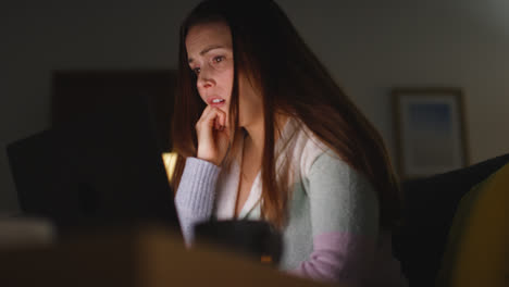 Anxious-Woman-Sitting-On-Sofa-At-Home-At-Night-Looking-At-Laptop-Concerned-About-Social-Media-Or-Bad-News-8